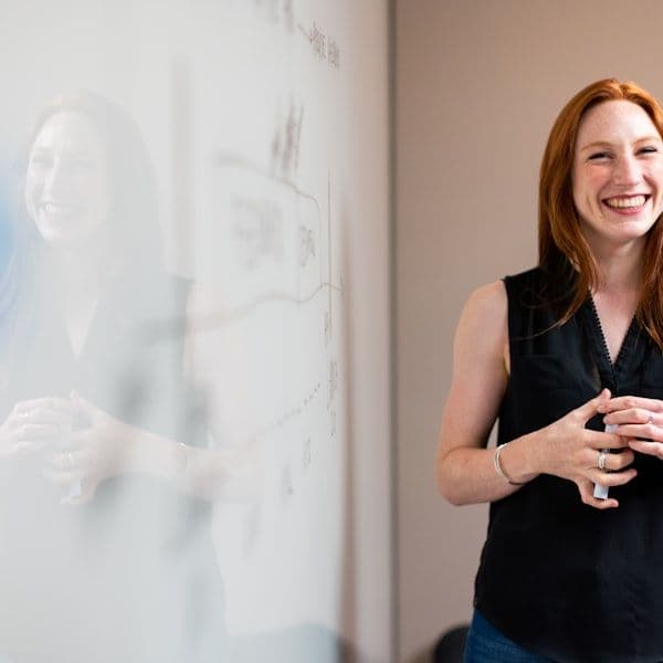 smiling woman presenting at whiteboard